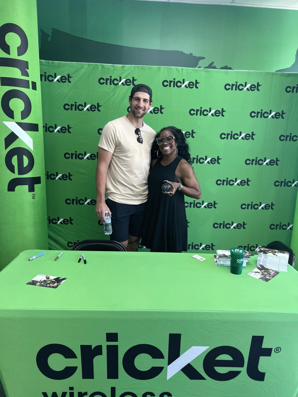 A professional hockey player posing with a fan at a sponsor booth during a brand appearance