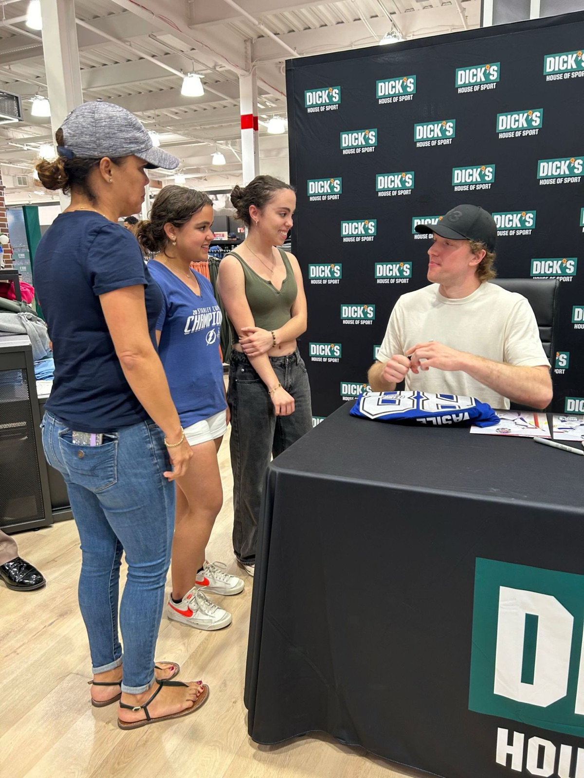 A professional hockey player signing autographs for fans at a sporting goods store event